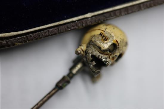 A 19th century French? base metal and cream enamel skull head stick pin, in the manner of Trouve & Cadet-Picard, overall 73mm.